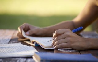 Young women and education, close up of hands of girl studying for college exam in park. Side view, copy space